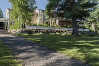 a pathway with rocks that have been placed near a house and trees in the background