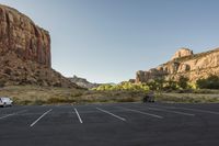 the car is sitting in the empty parking lot near a mountain range and several bushes