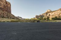 the car is sitting in the empty parking lot near a mountain range and several bushes