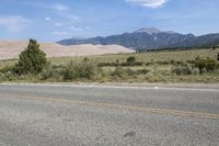 the motorcycle is parked in the side of the road in front of a mountain range