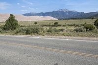 the motorcycle is parked in the side of the road in front of a mountain range