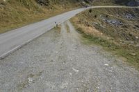 a motorcycle parked on a small mountain side road near mountains with no cars driving on it