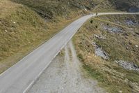 a motorcycle parked on a small mountain side road near mountains with no cars driving on it