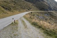 a motorcycle parked on a small mountain side road near mountains with no cars driving on it