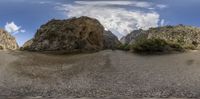 a wide angle fish - eye view of a rocky mountain side with one tree growing