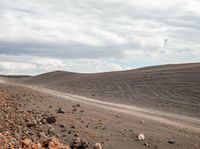 a red dirt road is in the distance, surrounded by rocks and scrubby dirt