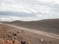 a red dirt road is in the distance, surrounded by rocks and scrubby dirt