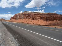 a long mountain road passing through the desert land on a clear, sunny day with blue skies