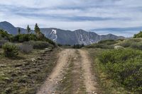 trail and a mountain with snow capped mountains in the distance along the road in the distance