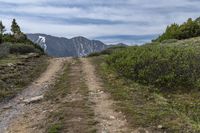 trail and a mountain with snow capped mountains in the distance along the road in the distance