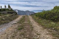 trail and a mountain with snow capped mountains in the distance along the road in the distance