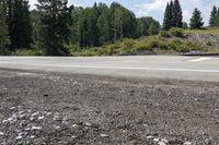 a lone motorcycle rider on the side of the road near the side of a mountain