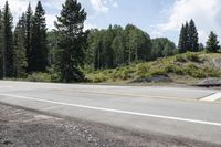 a lone motorcycle rider on the side of the road near the side of a mountain