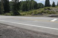 a lone motorcycle rider on the side of the road near the side of a mountain