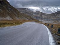 a black and white motorcycle is driving down a curvy road between the mountains