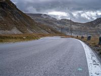 a black and white motorcycle is driving down a curvy road between the mountains