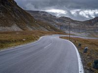 a black and white motorcycle is driving down a curvy road between the mountains