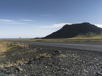 a motorcycle traveling past the peak of a hill in an arid field with dirt on both sides