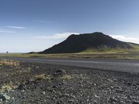 a motorcycle traveling past the peak of a hill in an arid field with dirt on both sides