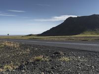 a motorcycle traveling past the peak of a hill in an arid field with dirt on both sides