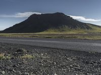 a motorcycle traveling past the peak of a hill in an arid field with dirt on both sides