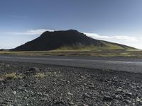 a motorcycle traveling past the peak of a hill in an arid field with dirt on both sides