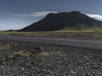 a motorcycle traveling past the peak of a hill in an arid field with dirt on both sides