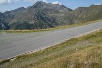 a motorcycle parked on a small mountain side road near mountains with no cars driving on it