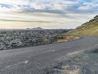 a motorcycle rider on an empty open road in front of the sun, and mountains