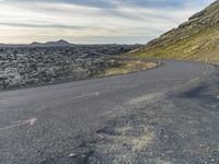 a motorcycle rider on an empty open road in front of the sun, and mountains