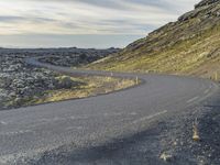 a motorcycle rider on an empty open road in front of the sun, and mountains