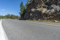 a motorcycle is on a paved highway with a lake in the background with a large cliff