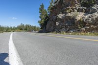 a motorcycle is on a paved highway with a lake in the background with a large cliff