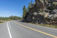 a motorcycle is on a paved highway with a lake in the background with a large cliff