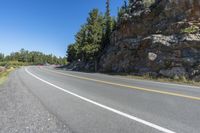 a motorcycle is on a paved highway with a lake in the background with a large cliff