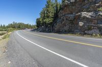 a motorcycle is on a paved highway with a lake in the background with a large cliff