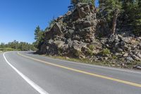 a motorcycle is on a paved highway with a lake in the background with a large cliff