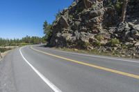 a motorcycle is on a paved highway with a lake in the background with a large cliff