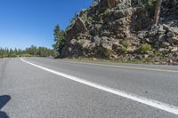 a motorcycle is on a paved highway with a lake in the background with a large cliff