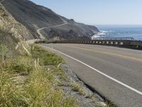 a camera sits at the edge of a scenic mountain highway beside the ocean in california