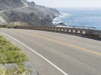 a camera sits at the edge of a scenic mountain highway beside the ocean in california