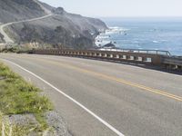 a camera sits at the edge of a scenic mountain highway beside the ocean in california