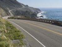 a camera sits at the edge of a scenic mountain highway beside the ocean in california