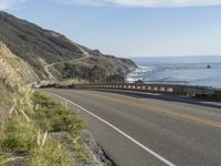 a camera sits at the edge of a scenic mountain highway beside the ocean in california