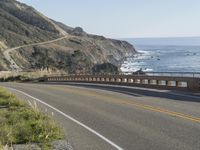 a camera sits at the edge of a scenic mountain highway beside the ocean in california