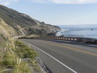 a camera sits at the edge of a scenic mountain highway beside the ocean in california