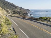 a camera sits at the edge of a scenic mountain highway beside the ocean in california