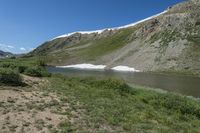 a scenic mountain lake, with a lot of water and grass below it in a field