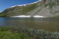 a scenic mountain lake, with a lot of water and grass below it in a field