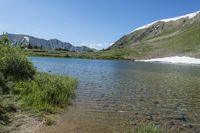 a scenic mountain lake, with a lot of water and grass below it in a field